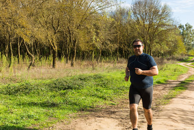 Portrait of man in sunglasses running on dirt road