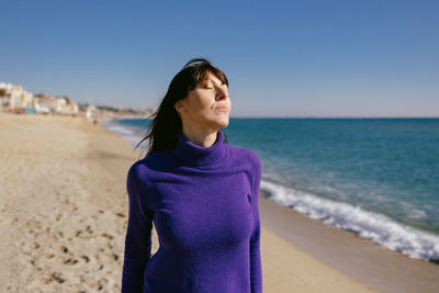 Beautiful mature woman relaxing breathing fresh air on a sunny winter day at the beach