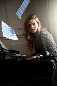 Young woman looking away while playing piano at home