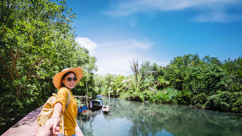 Portrait of young woman standing against lake