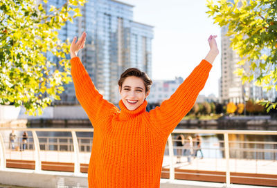 Rear view of woman with arms raised standing against trees