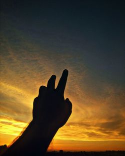 Close-up of silhouette hand against sky during sunset