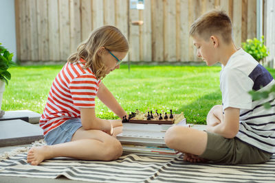 Rear view of boy sitting on outdoors