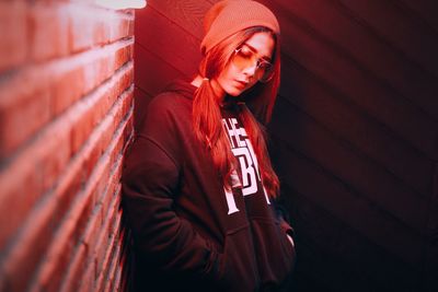 Portrait of young woman standing against wall