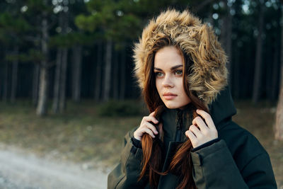 Portrait of young woman standing against tree