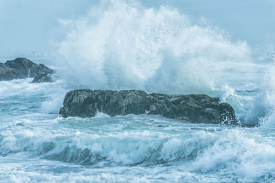 Waves splashing on sea against sky