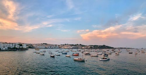 Sailboats moored in harbor at sunset