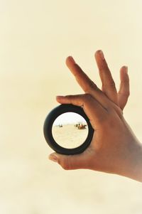 Close-up of hand holding camera against sky