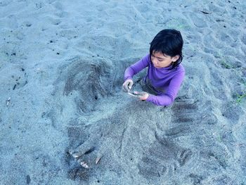 A girl is playing in the sand on the beach