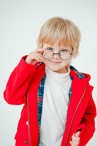 Blond boy with glasses. a beautiful blonde child. boy in a red coat.
