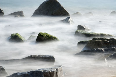 View of rocks at beach in foggy weather