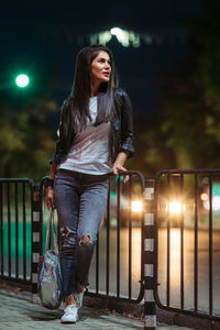 Young woman with arms outstretched at night