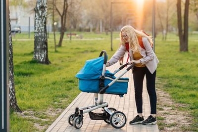 Mom in glasses walks with a stroller in the park