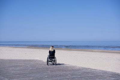 Rear view of man on beach against sky