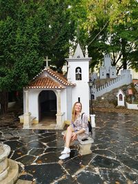 Full length of smiling woman sitting outside building