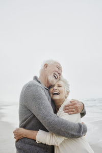 Laughing senior couple embracing at the sea