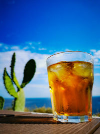 Close-up of drink on table against blue sky