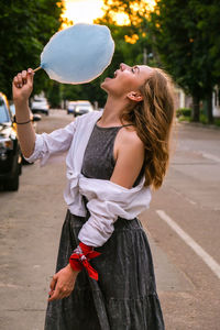 Young woman holding umbrella while standing in park