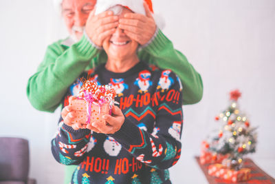 Portrait of young woman holding gift against white background