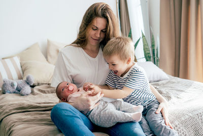 Young mother with children at home. newborn sister and brother toddler with parent.