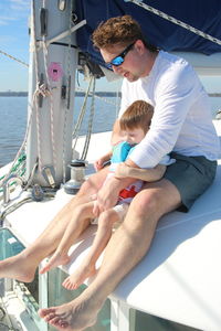 Mother and daughter sitting on sea shore