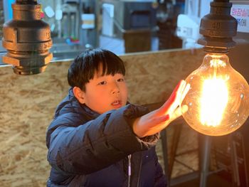 Boy touching illuminated light bulb