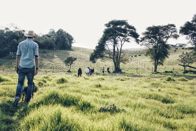 Man with dog walking on field against trees