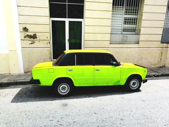 Yellow car on street against building in city