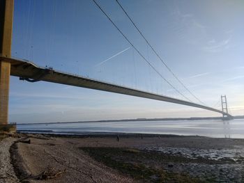 Suspension bridge over sea against sky