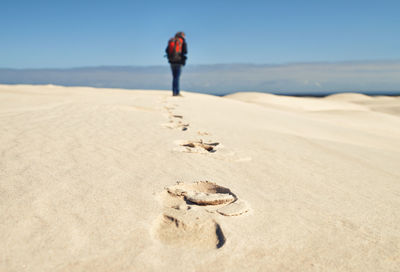 Rear view of man walking on sand at beach