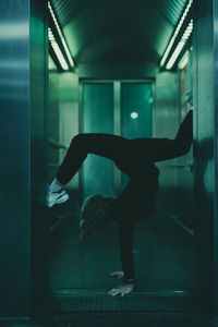 Full length of woman exercising in dark corridor