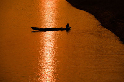 Silhouette person in boat on sea during sunset
