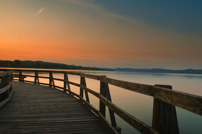 Pier over lake against sky during sunset