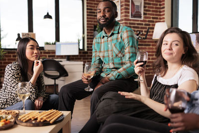 Portrait of smiling friends using digital tablet while sitting at home