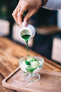 Midsection of person pouring drink in glass on table