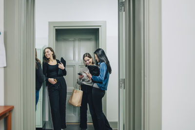 Cheerful female high school students in corridor at school