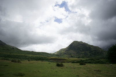 Scenic view of field and mountains against sky