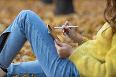 Midsection of woman holding hands sitting outdoors