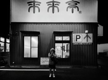 Full length rear view of woman standing against wall