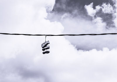 Low angle view of shoes hanging against sky