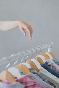 A woman's hand holds a hanger with clothes in the wardrobe. recycling. stylist or merchandiser