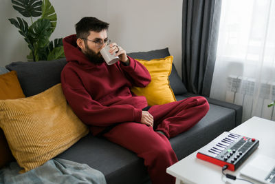 Young woman using phone while sitting on sofa at home