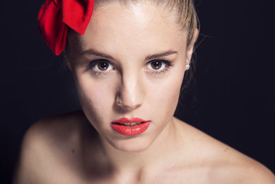 Close-up portrait of young woman against black background