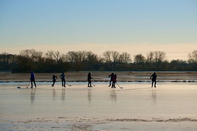 People walking at beach against clear sky