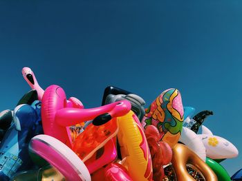 Close-up of various inflatables beach toys on beach against clear summer sky.