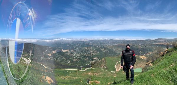 Rear view of man standing on mountain against sky