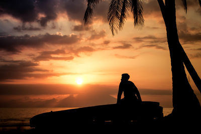 Silhouette person standing on beach against sky during sunset