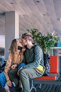 Kissing couple of tourists are waiting for their flight at an empty airport 