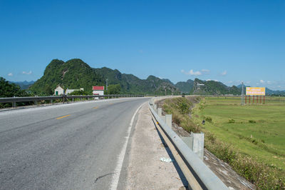 Road by trees against clear sky