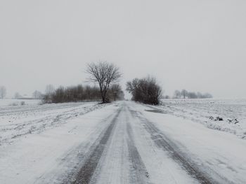 Snow covered road passing through forest